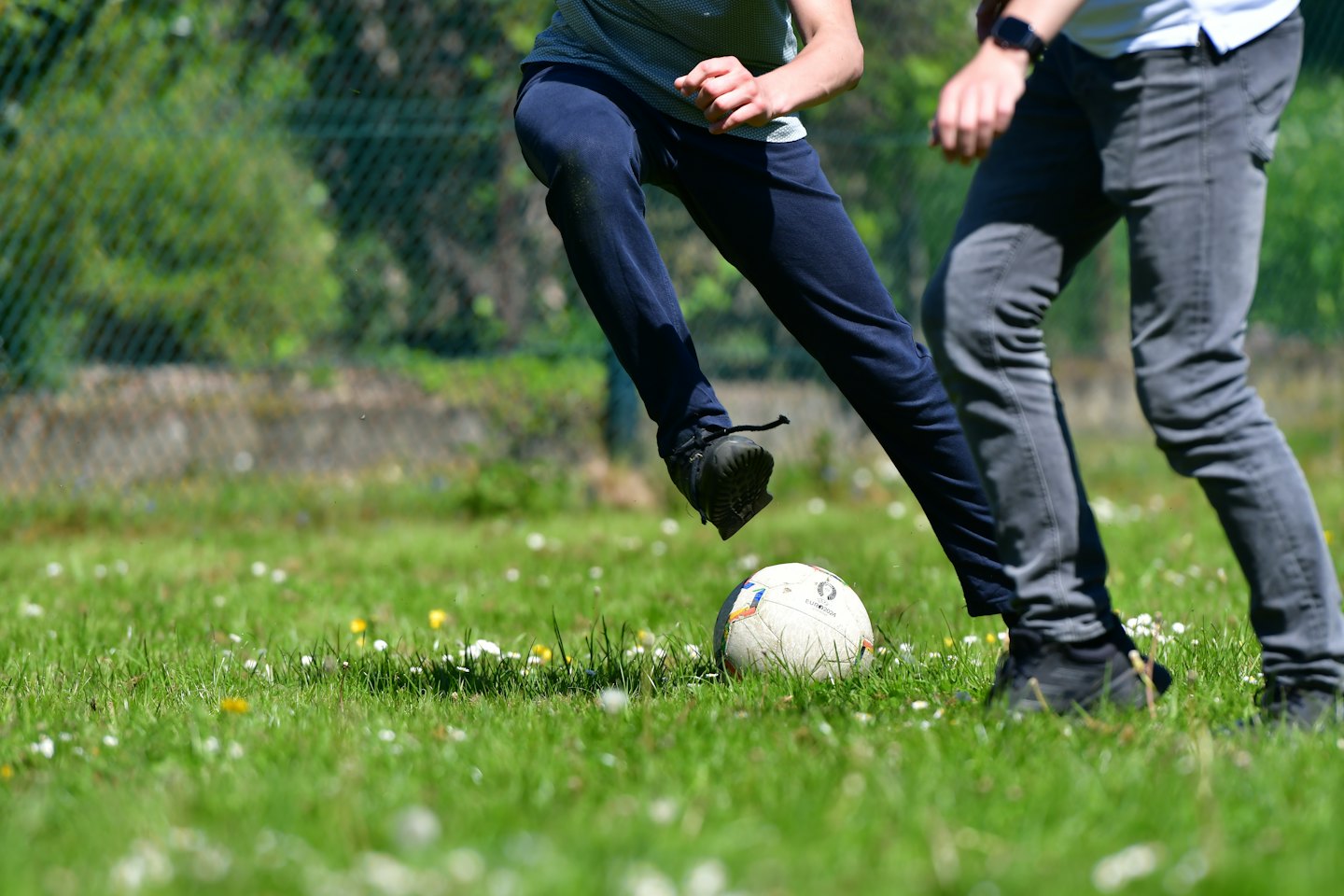 Due bambini giocano a calcio in un prato fiorito.